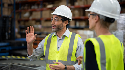 people wearing hard hats and safety vests in a warehouse